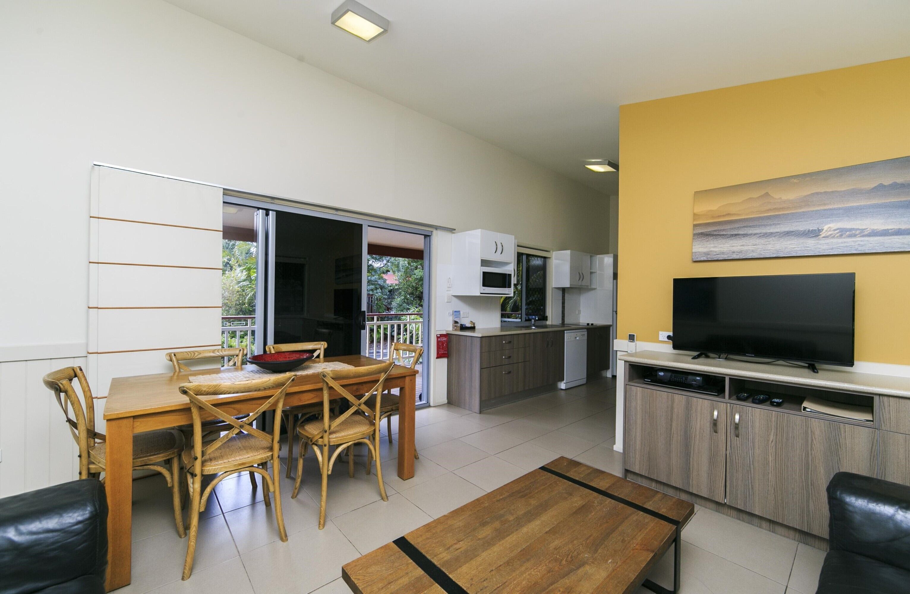 Uma sala de estar moderna com área de refeições, cozinha e televisão.