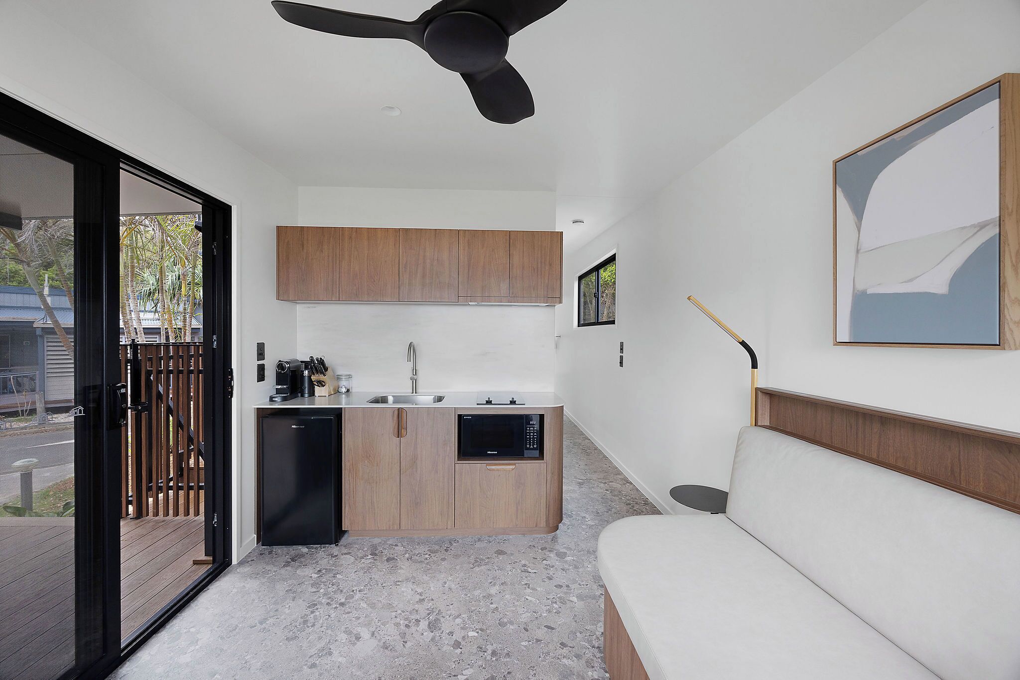 A compact living space with a kitchenette, a sofa, and a ceiling fan.