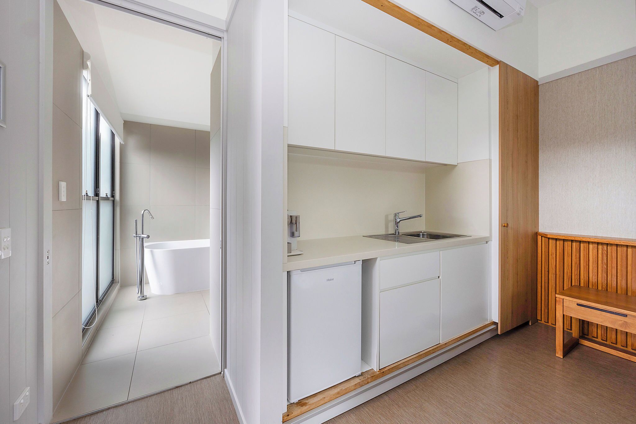 A modern kitchen with white cabinets, a built-in sink, and a compact refrigerator.