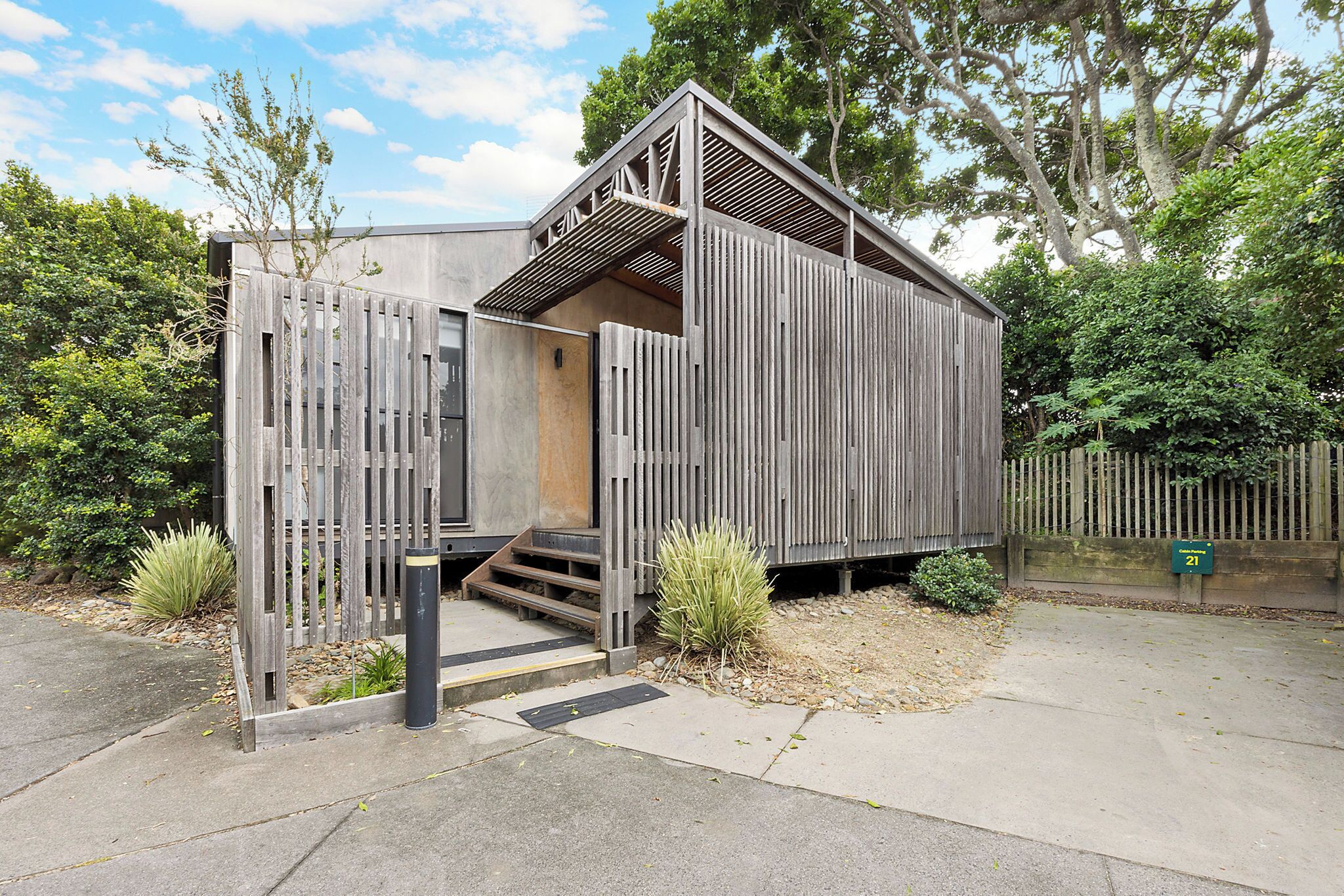A small, wooden structure with a sloped roof and a set of stairs leading to an entrance.