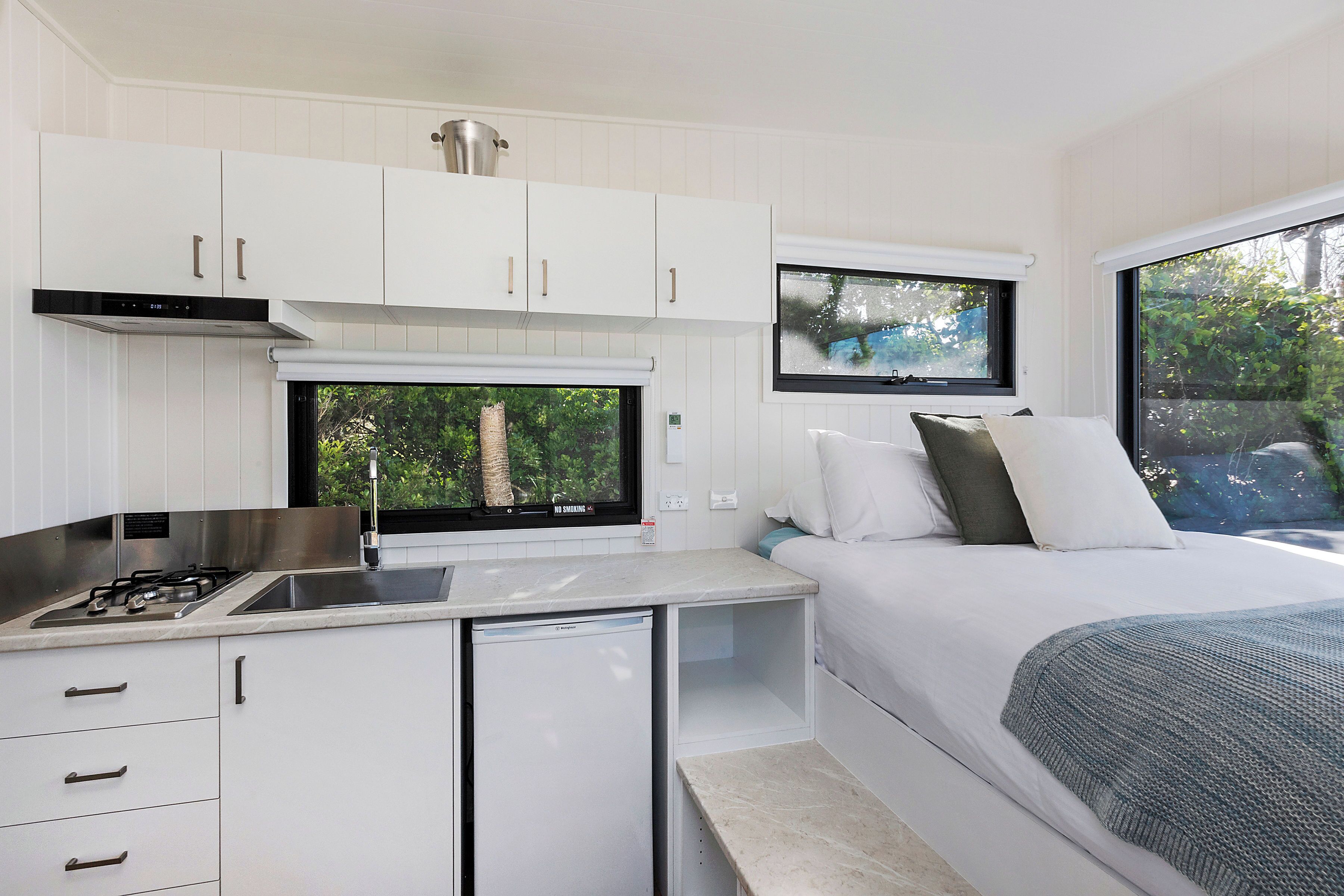 A compact bedroom with a bed, a TV, and a small kitchenette.