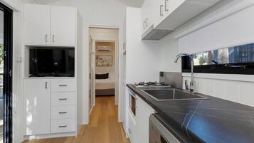 A modern kitchen with white cabinetry, a black countertop, and a built-in oven.