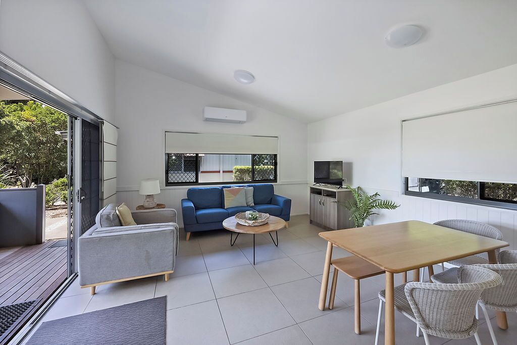 A modern living room with a sofa, coffee table, and dining table.
