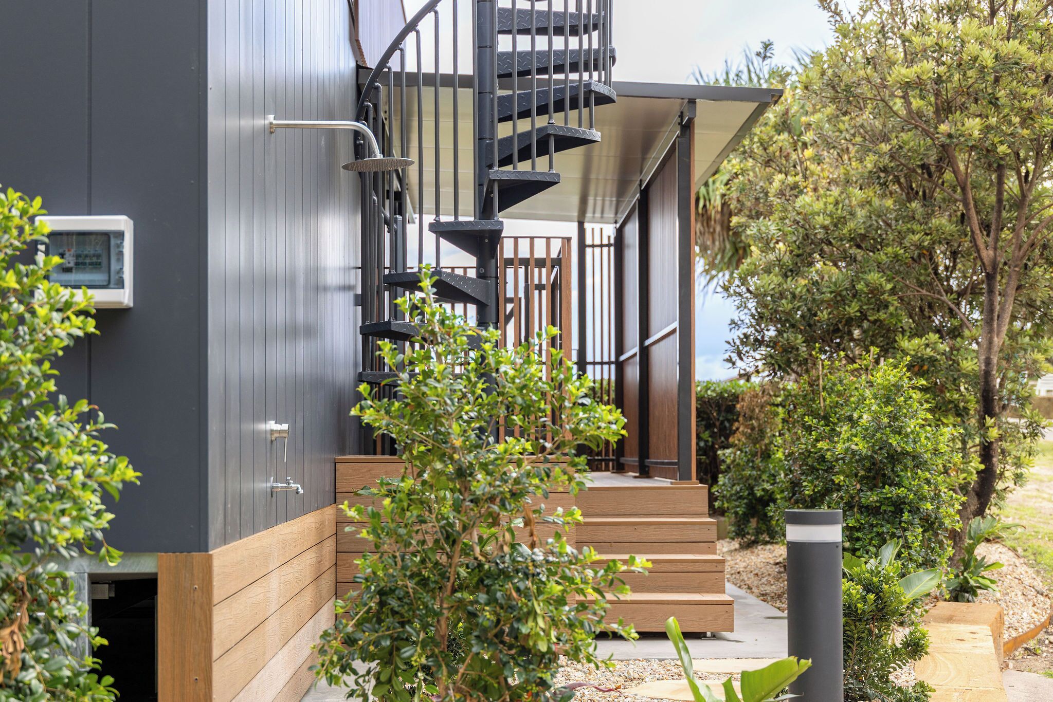 A modern building with a spiral staircase, wooden steps, and a metal railing.