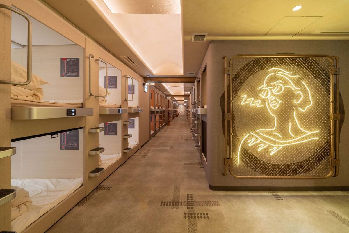 A train carriage with bunk beds, a neon sign, and a corridor.