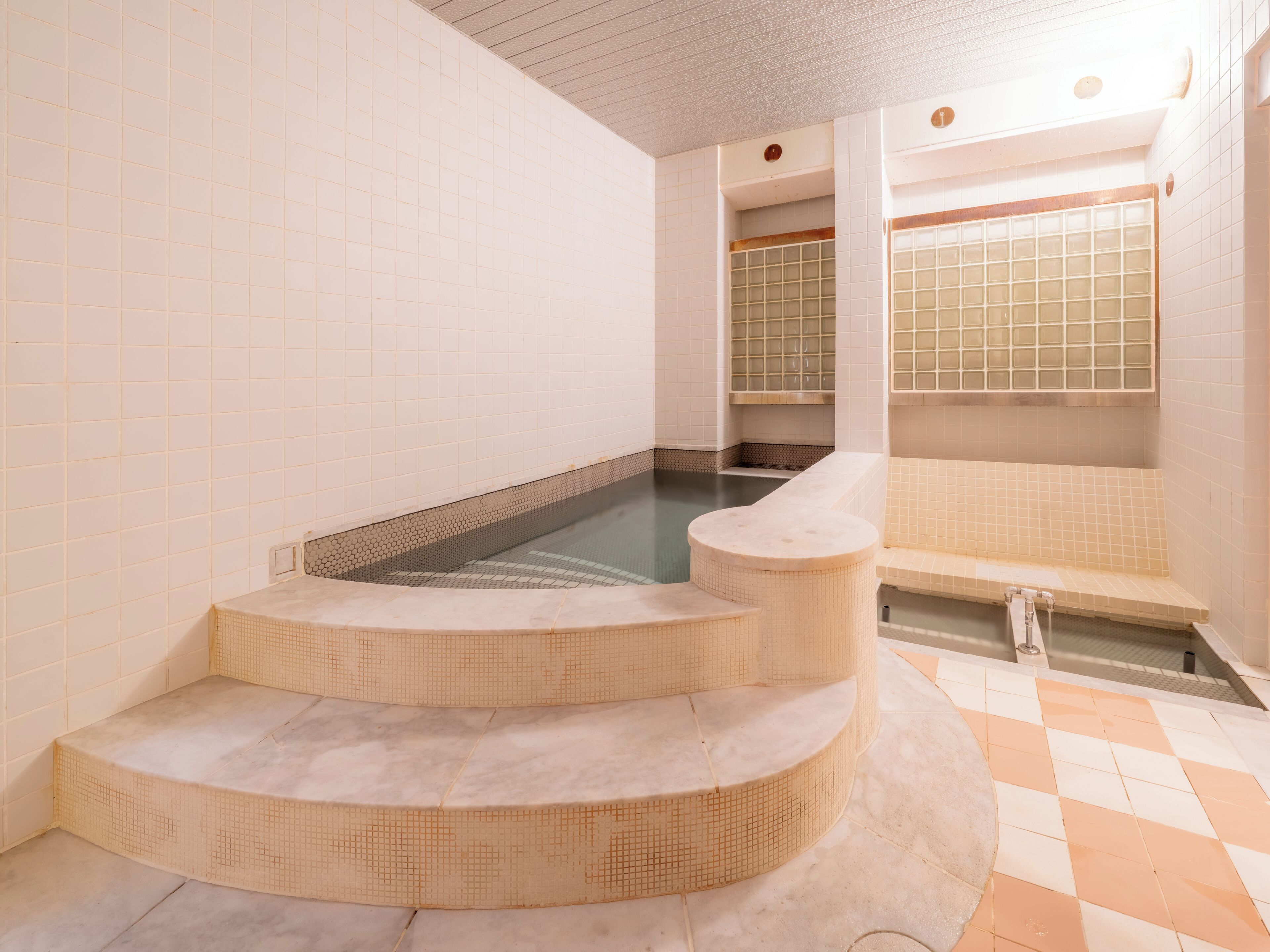A spa area with a hot tub, a seating area, and a tiled floor.
