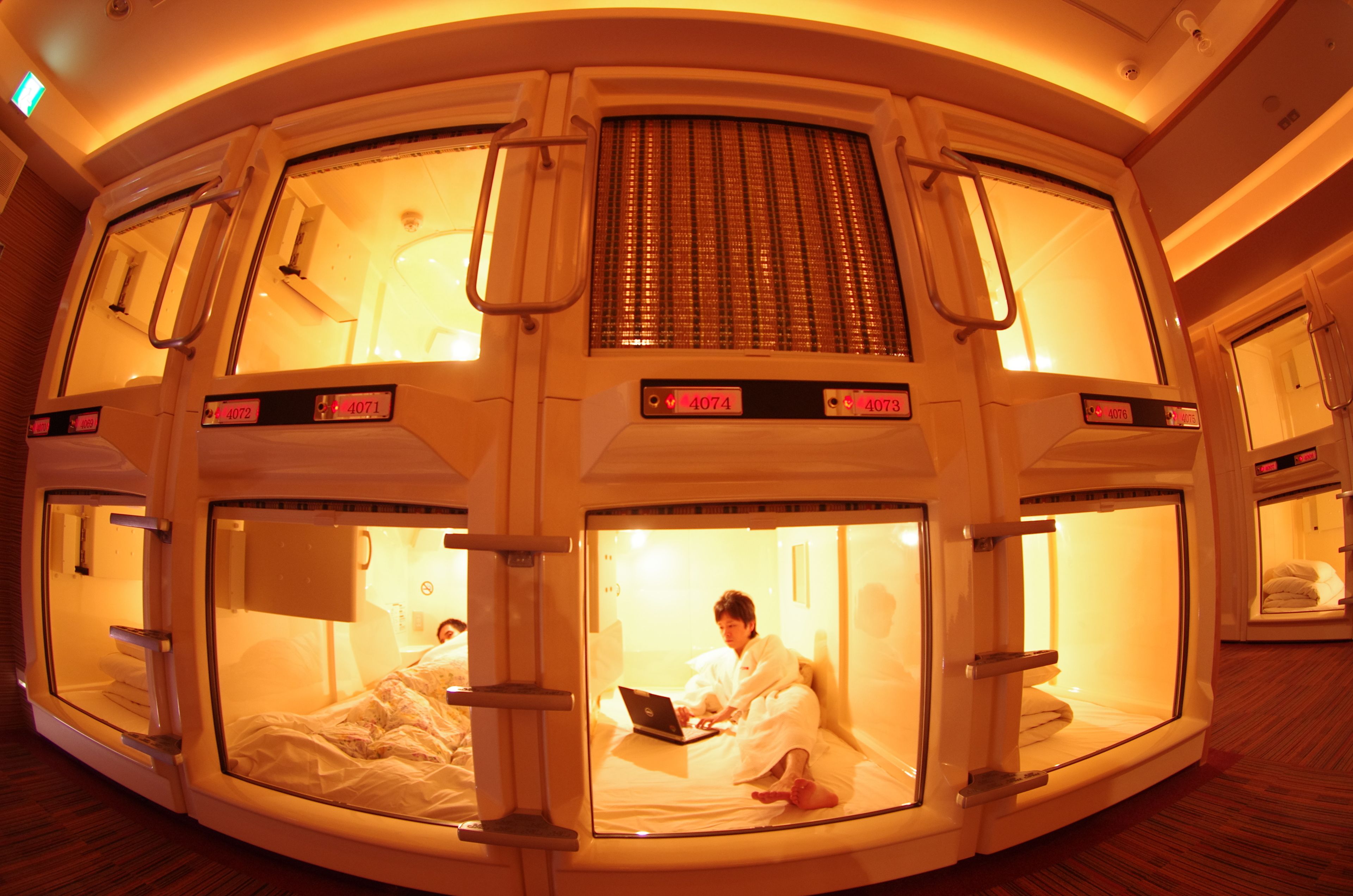A hotel room with a unique circular layout, multiple beds, and a laptop on one bed.