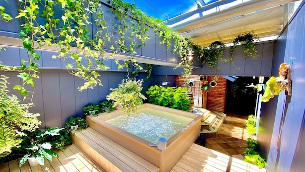 Um espaço ao ar livre moderno com hidromassagem, deck de madeira e vegetação exuberante.