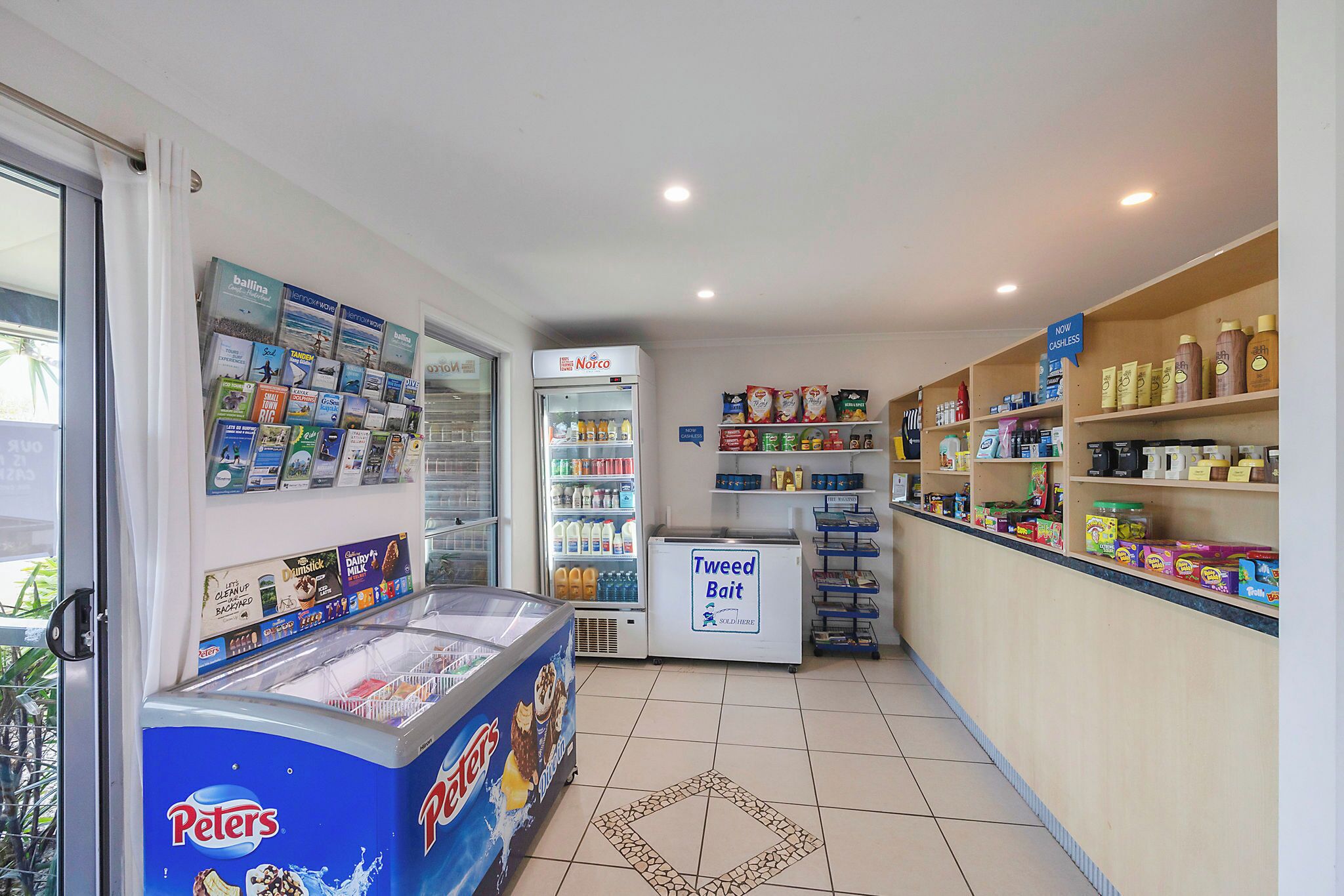 A small convenience store with a freezer, refrigerated section, and shelves stocked with snacks and beverages.
