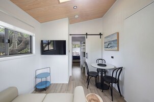 Un espacio habitable moderno y funcional con comedor, televisor montado en la pared y vistas al exterior a través de una ventana.