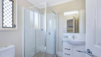 A modern bathroom with a glass shower enclosure, a white sink, and a mirror above the sink.