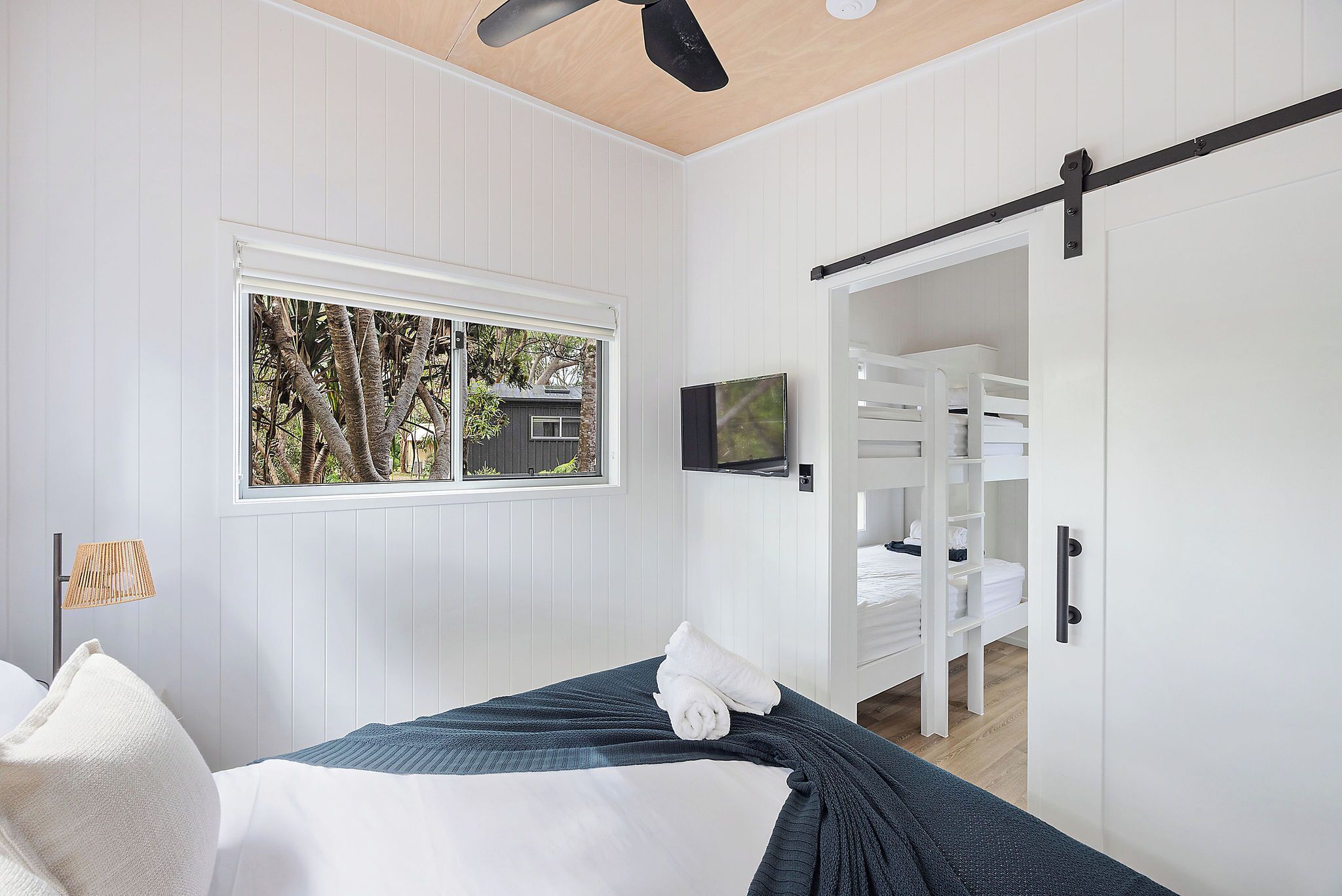 A bedroom with a bed, a TV, a window, and a wardrobe.