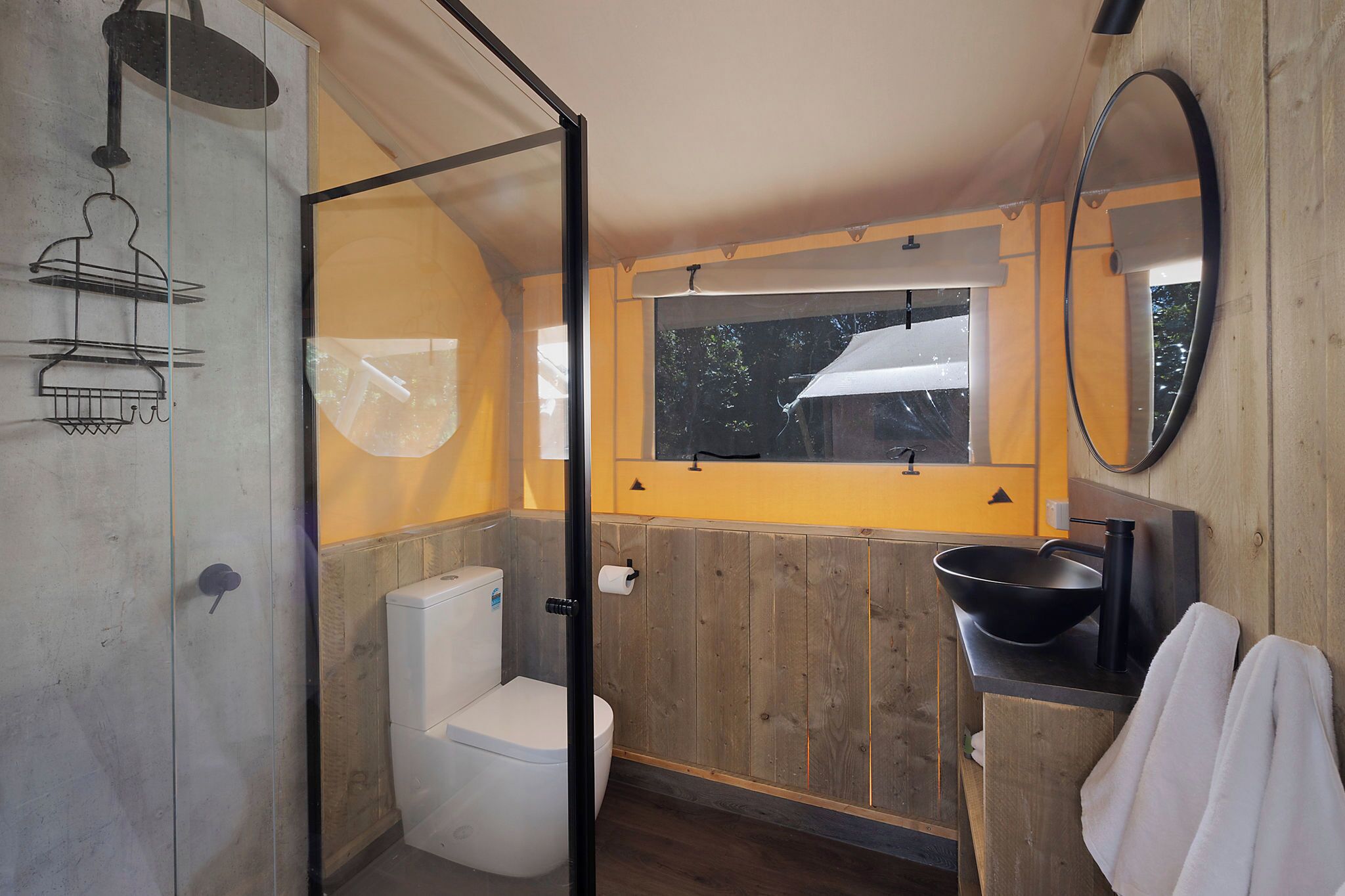 A bathroom with a toilet, a shower, a sink, and a mirror.