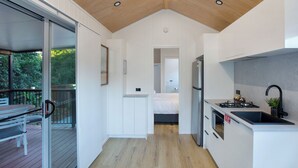 Une cuisine compacte équipée d’un four encastré, d’un évier et d’un petit coin repas avec une table et des chaises.