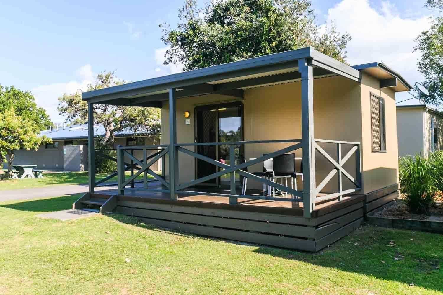 Une petite construction d’un seul étage, dotée d’un espace extérieur abrité, d’une porte et d’une fenêtre.