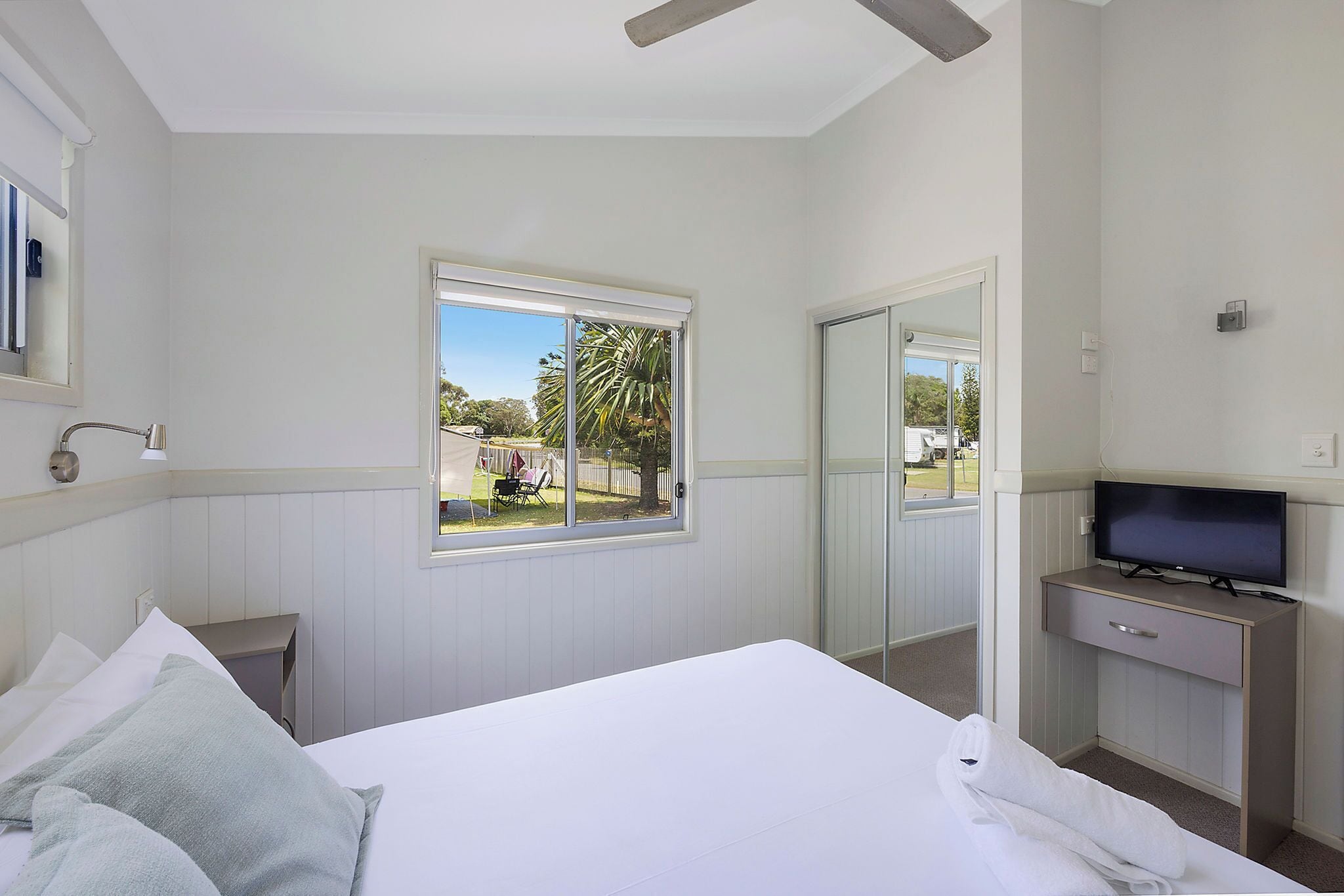 Habitación de hotel con cama, televisión, escritorio y ventana con vistas al exterior.