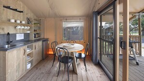 Une cuisine avec un plan de travail en bois, un évier et une table à manger avec des chaises. Il y a une fenêtre donnant sur l’extérieur.