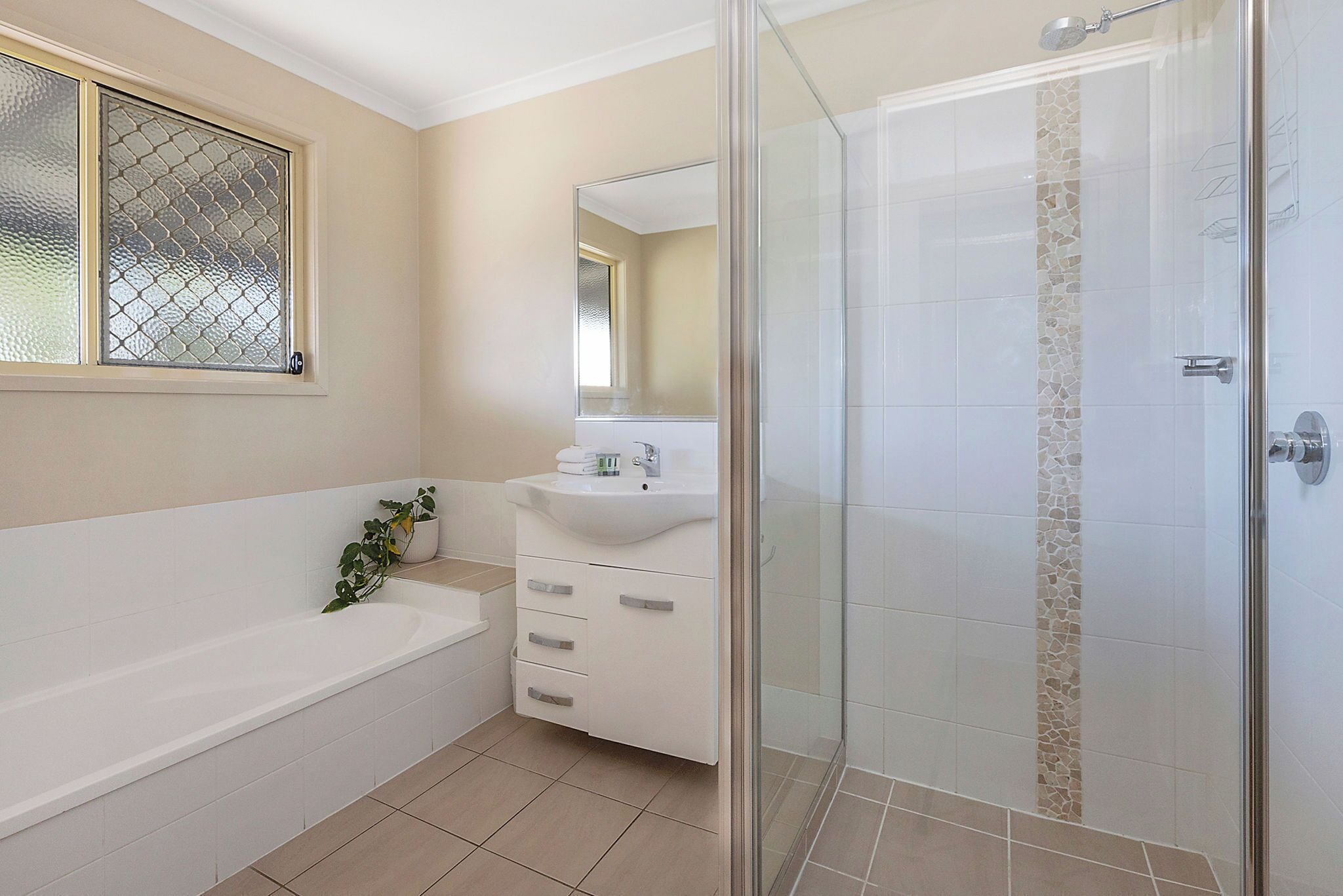 A modern bathroom with a bathtub, a glass-enclosed shower, and a vanity with a mirror.