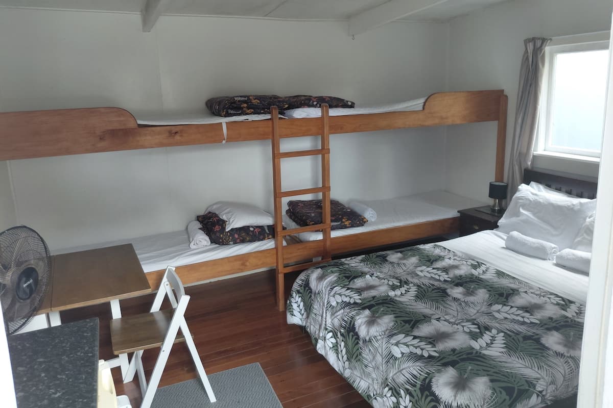 A bunk bed room with a desk, chair, and a window with curtains.