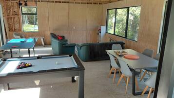 Une salle de loisirs équipée d’une table de billard, d’un coin salon et d’une table avec des chaises.