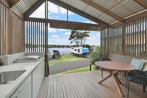 Un espacio al aire libre techado con una terraza de madera, una mesa y sillas.