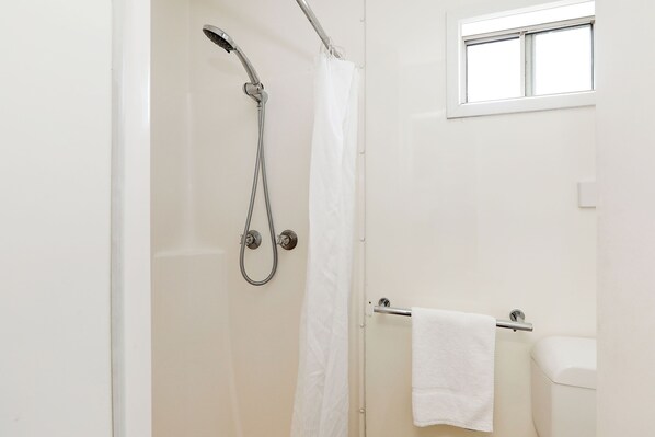 Un baño con ducha, inodoro y ventana.
