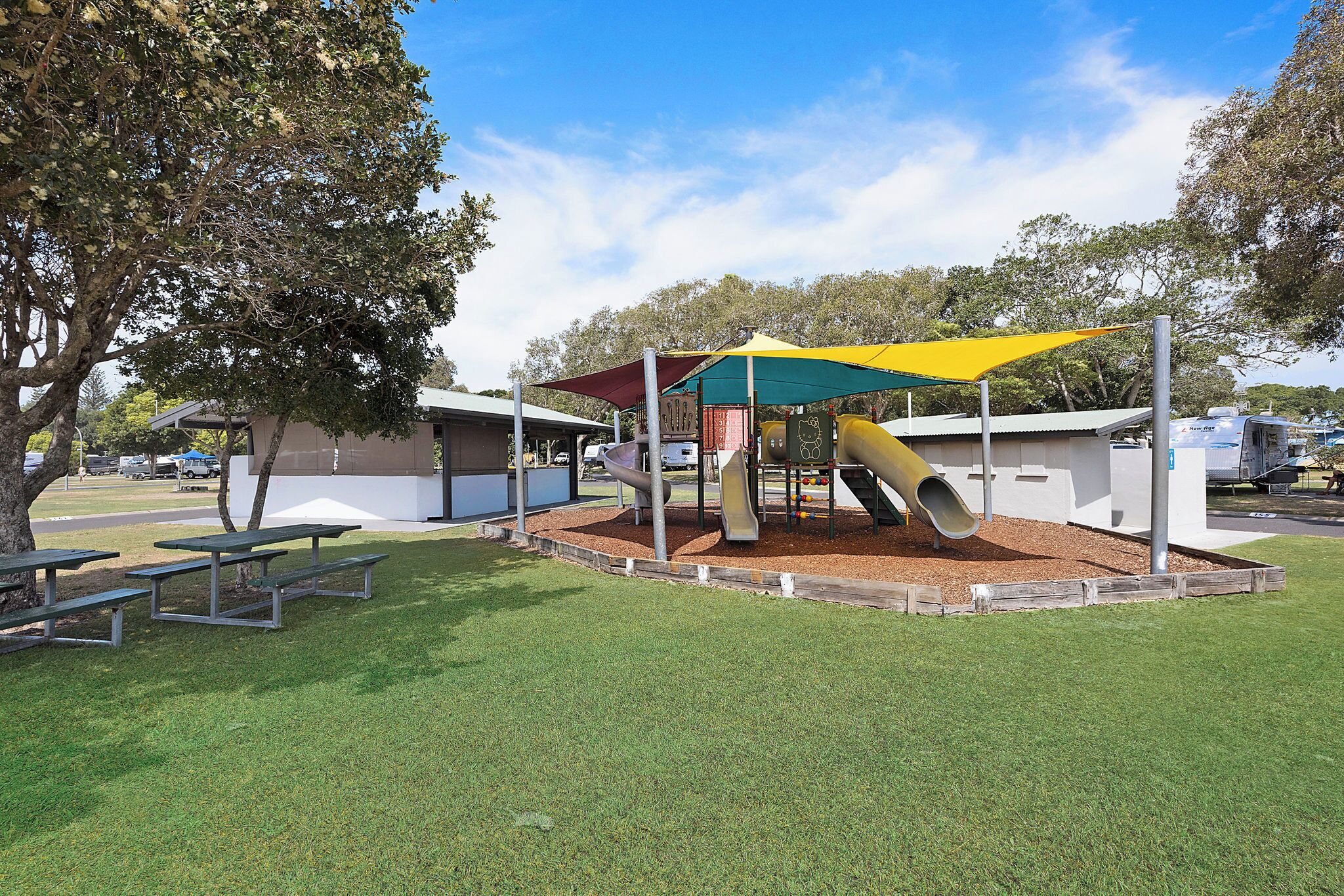 A playground with a slide and picnic tables.