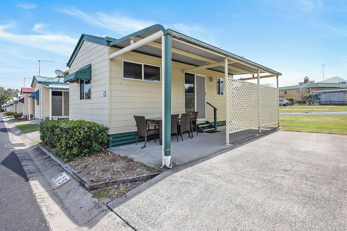 A row of mobile homes with a covered patio area, outdoor seating, and a small garden.