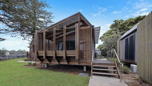 A modern wooden building with a sloped roof and open sides, featuring a staircase leading to a deck area. - Reflections Evans Head - Holiday Park (Evans Head)