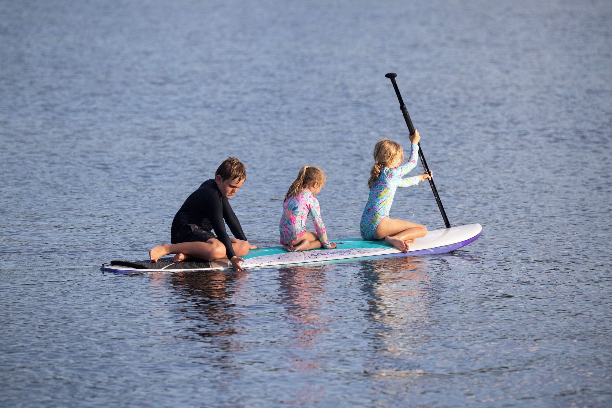 Tres personas en una tabla de paddleboard sobre el agua.