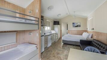 A compact hotel room with bunk beds, a kitchenette, a dining area, and a single bed.