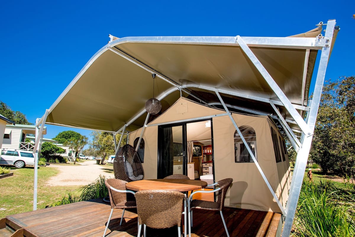 A tent-style accommodation with a wooden deck, outdoor seating, and a covered area.