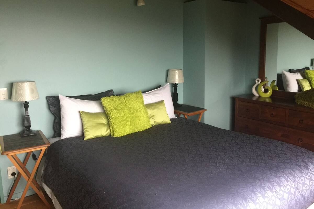 Un dormitorio con una cama, dos mesitas de noche, un aparador y un espejo.