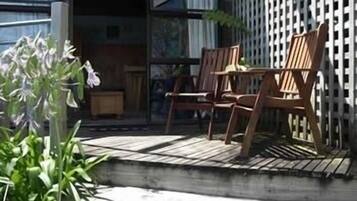 An outdoor seating area with wooden chairs and a table, surrounded by a wooden deck and a white fence.
