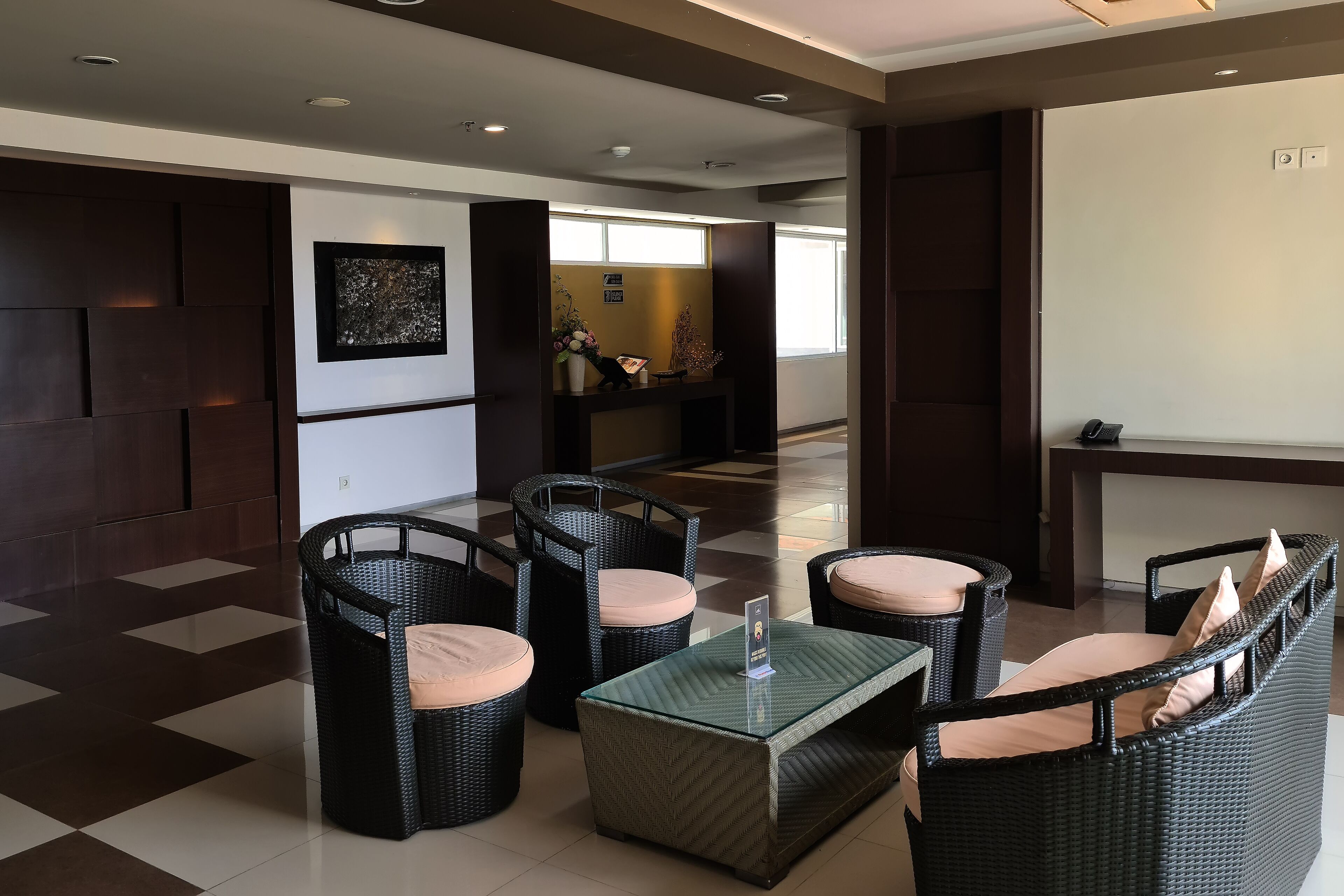 A lobby with wicker furniture, a glass coffee table, and a reception desk.