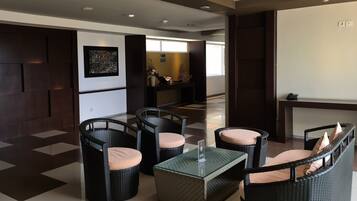 A lobby with wicker furniture, a glass coffee table, and a reception desk.