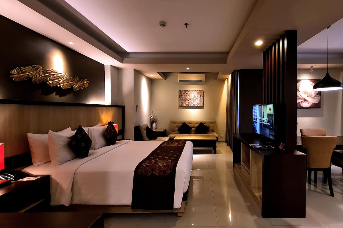 Una moderna camera d'albergo con un letto grande, una televisione, un divano e un'area pranzo.
