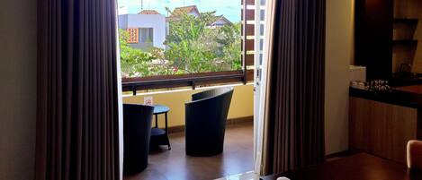 Habitación moderna con vistas a un jardín y edificios. Incluye una zona de comedor con mesa y sillas, y una kitchenette con mostrador y armarios.