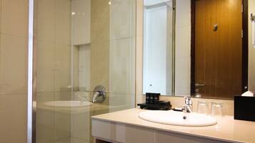 Een moderne badkamer met een douchecabine van glas, een grote spiegel en een wastafel met handdoekhouder.