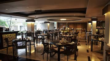 A modern restaurant with a central bar, multiple dining tables, and a mix of seating arrangements.