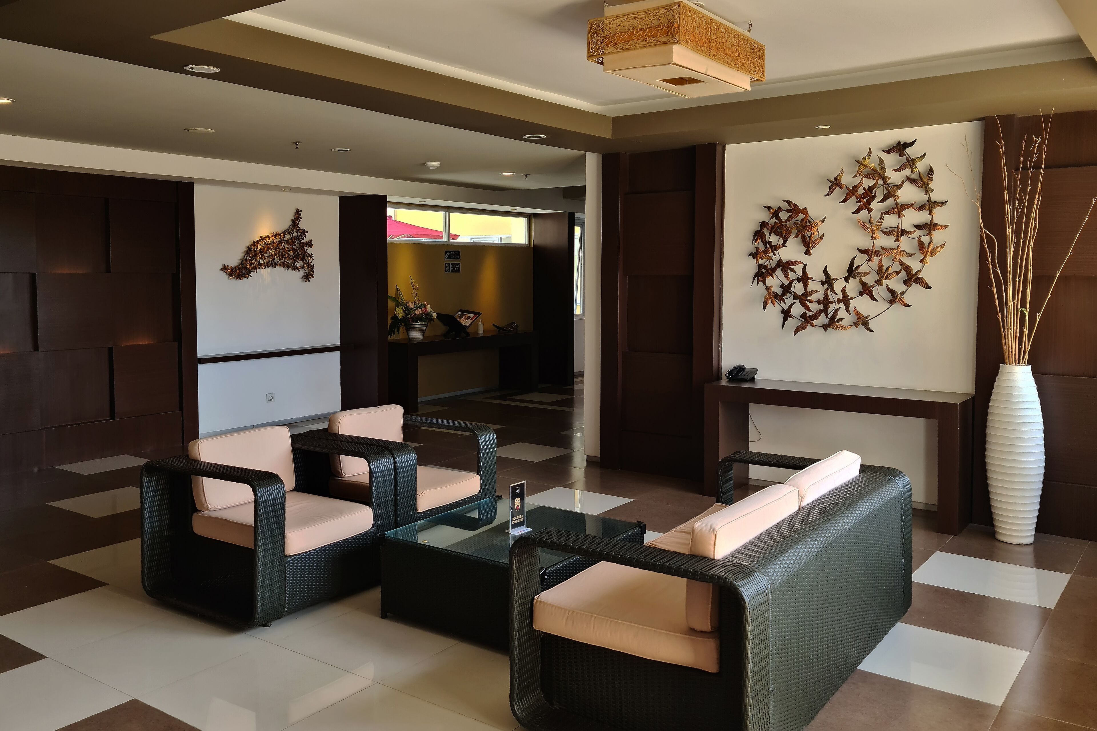 A modern lobby with wicker furniture, a reception desk, and decorative wall art.