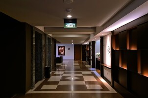 A hotel corridor with an exit sign, a reception desk, and a patterned floor.