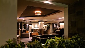 A modern lobby with a central seating area, a reception desk, and a decorative ceiling light. - The Kana Kuta (Kuta)