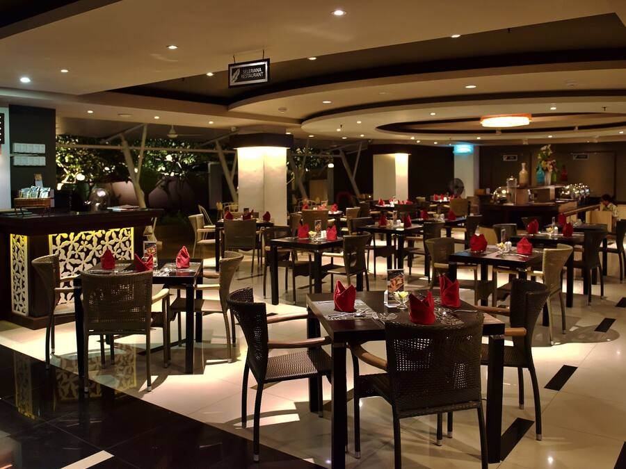 A modern restaurant with multiple dining tables and chairs, a bar area, and a sign indicating it is part of a hotel.