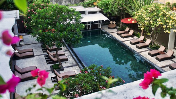 A pool area with lounge chairs and a small waterfall feature. - The Kana Kuta (Kuta)