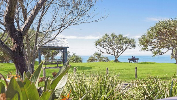Un área verde con un pabellón, una mesa de picnic y vistas al mar.