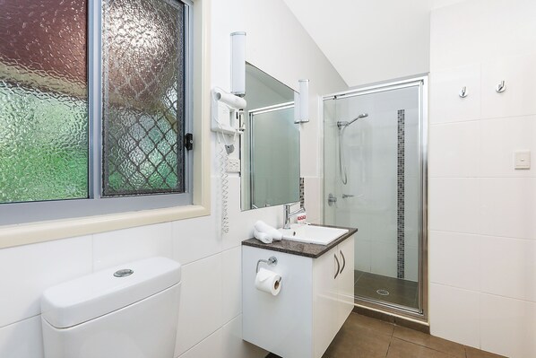 Un baño moderno con cabina de ducha de vidrio, lavamanos blanco y retrete.
