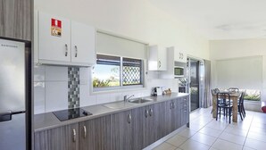 Una cocina moderna con armarios grises, un refrigerador de acero inoxidable y un comedor con mesa y sillas.