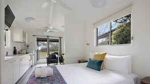 Un dormitorio con cama, ventana, ventilador de techo y vistas al exterior.