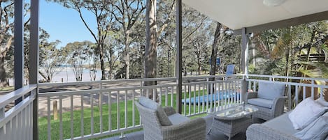 Eine überdachte Terrasse im Freien mit Korbmöbeln und Blick auf die Umgebung.
